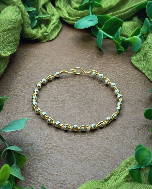 Handmade, wire-wrapped bracelet shaped like a wave, featuring silver beads.