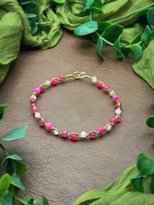 Handmade, wire-wrapped bracelet shaped like a wave, featuring light pink, mauve pink, and hot pink beads.