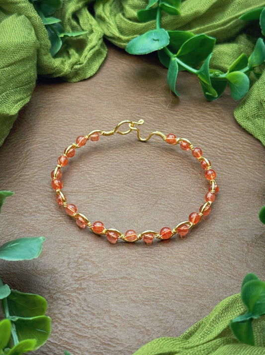 Handmade, wire-wrapped bracelet shaped like a wave, featuring pink dyed quartz gemstone beads.