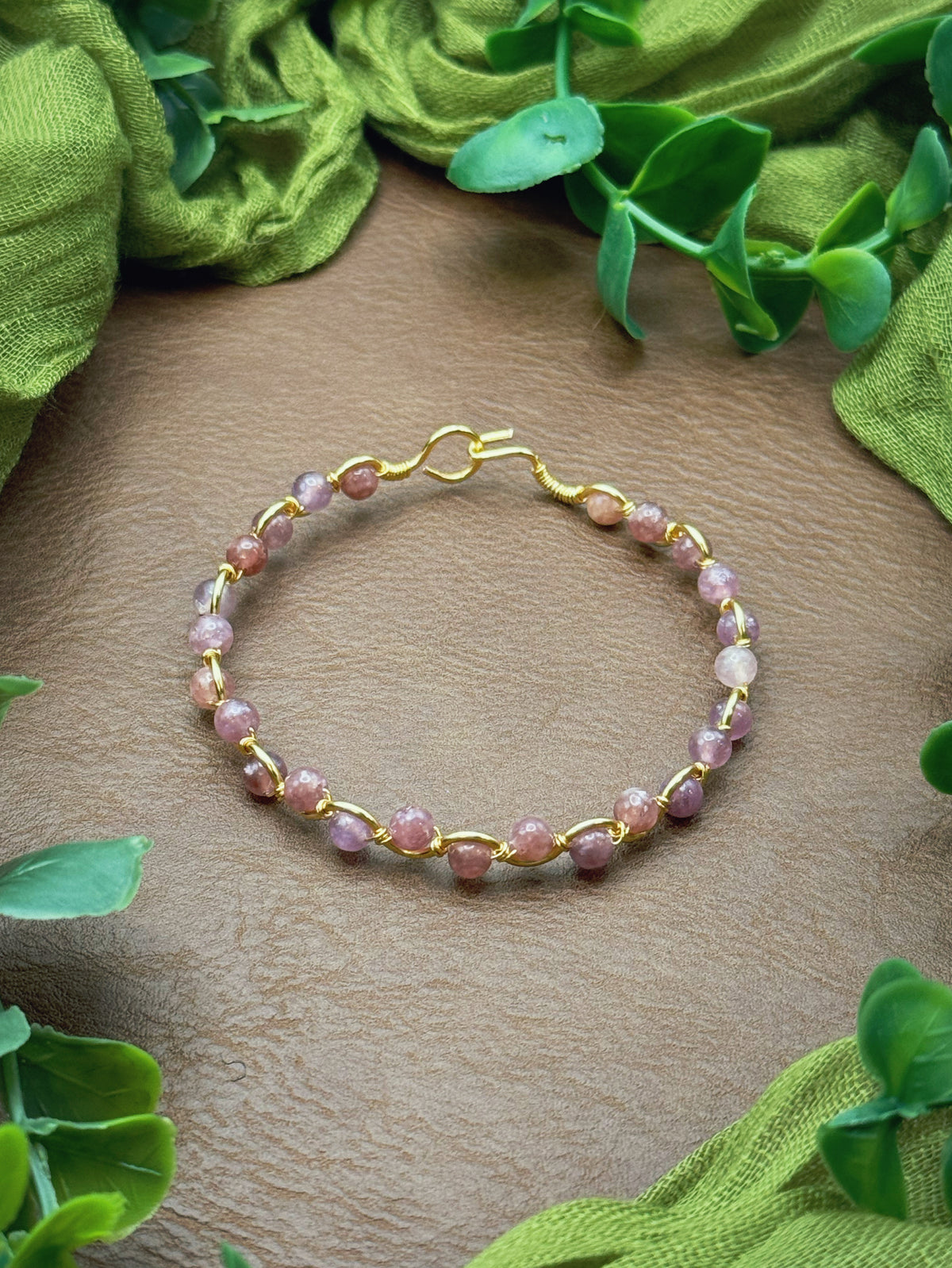Handmade, wire-wrapped bracelet shaped like a wave, featuring purplish pink lepidolite gemstone beads.
