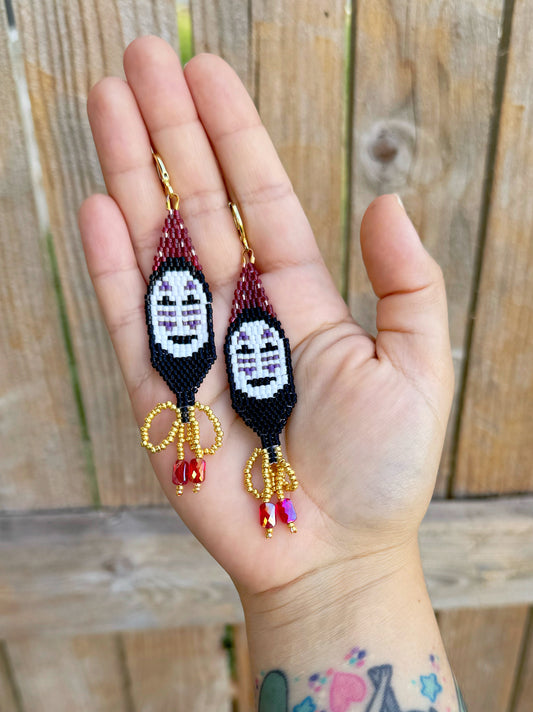 Handmade beaded earrings inspired by Spirited Away with a wooden fence background.