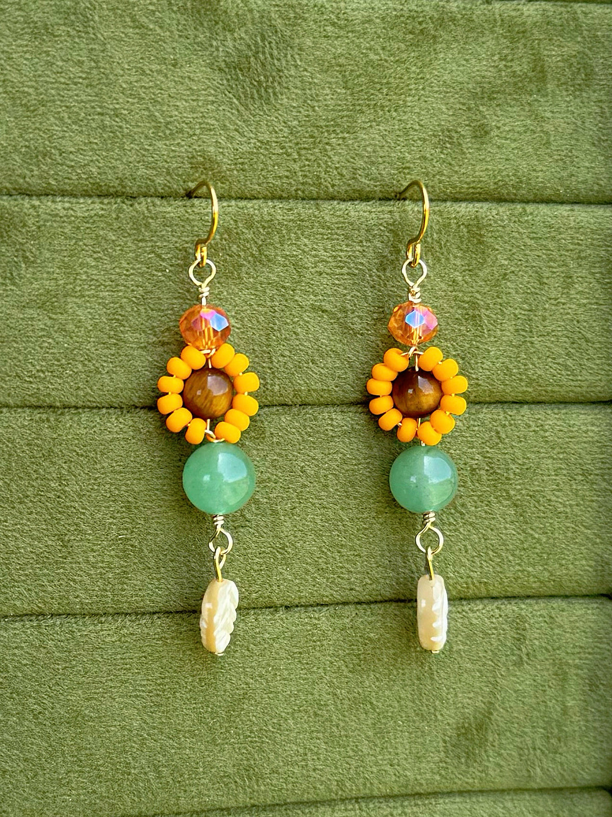 Handmade beaded floral earrings with gemstone and glass beads on an olive green velvet background.