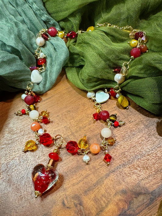 Colorful beaded necklace with heart charm on a wooden surface with green fabric in the background