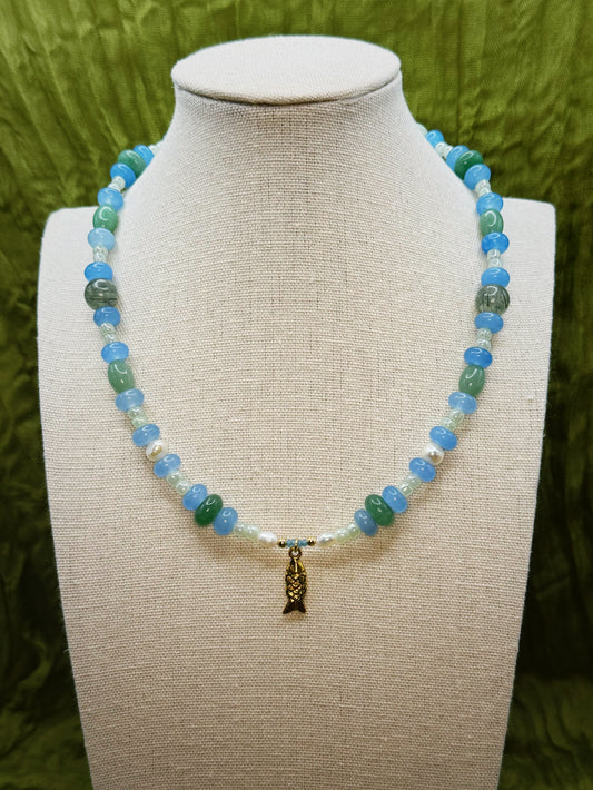 Necklace with blue and green beads on a mannequin bust against a green background