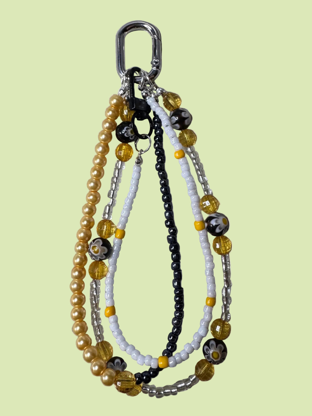 Handmade beaded bag charm keychain with a silver carabiner clip, featuring white, yellow, and black beads, and millefiore flower beads.