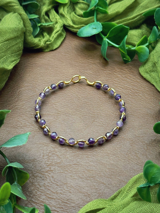 Handmade, wire-wrapped bracelet shaped like a wave, featuring amethyst purple beads.