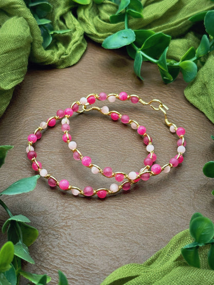 Handmade, wire-wrapped bracelet shaped like a wave, featuring light pink, mauve pink, and hot pink beads.