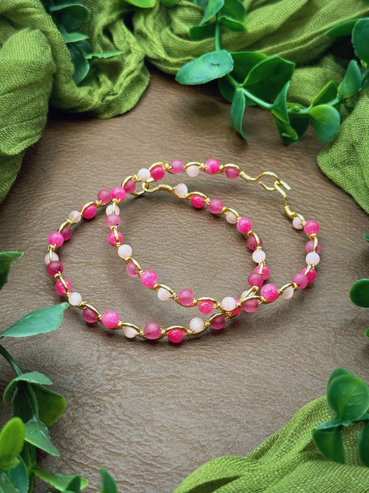 Handmade, wire-wrapped bracelet shaped like a wave, featuring light pink, mauve pink, and hot pink beads.