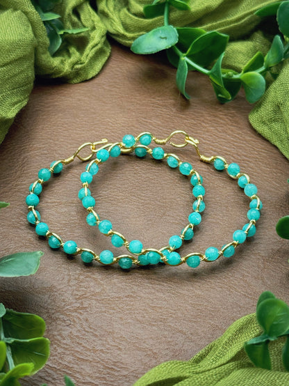 Handmade, wire-wrapped bracelet shaped like a wave, featuring aqua gemstone beads.