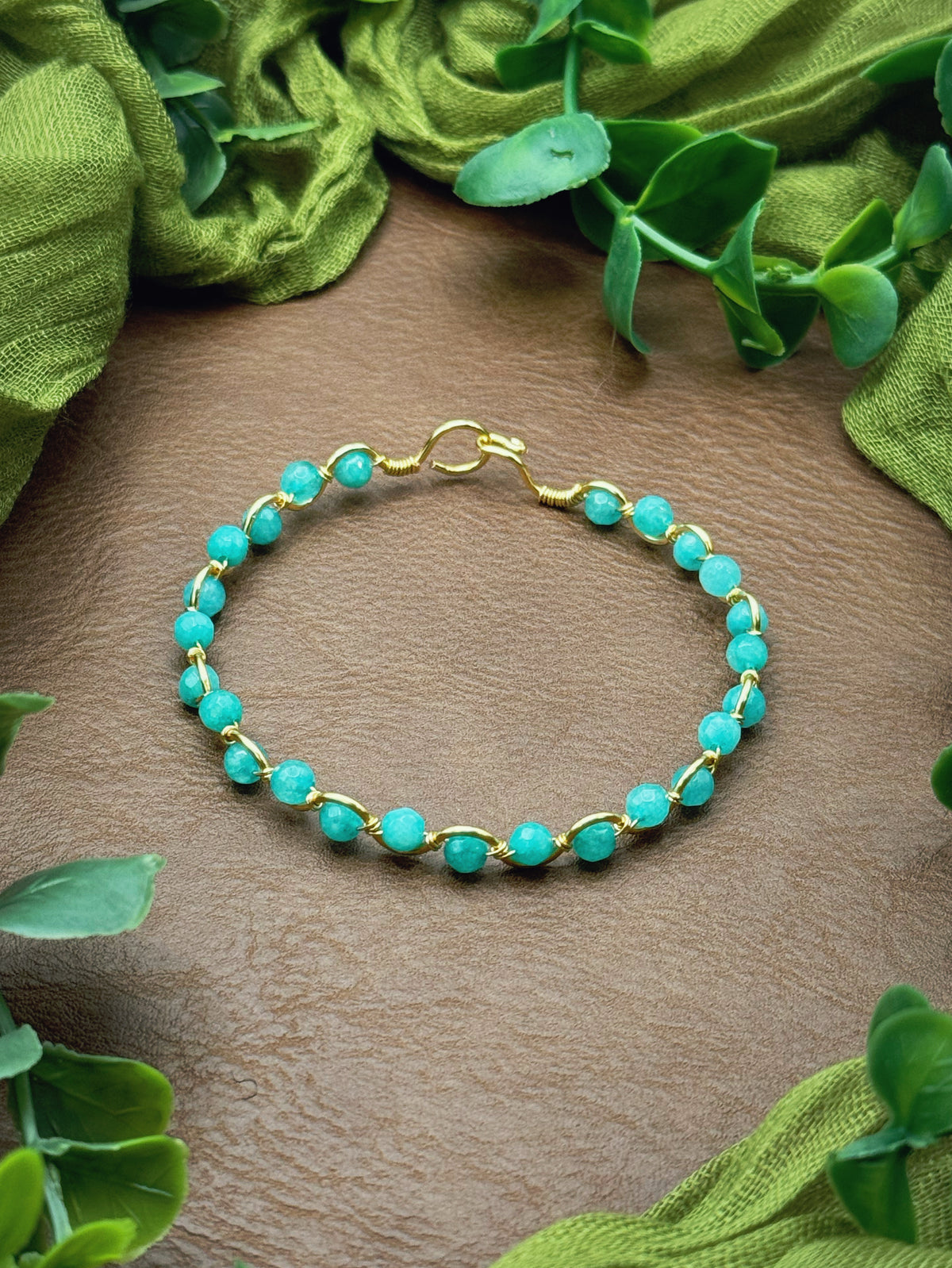 Handmade, wire-wrapped bracelet shaped like a wave, featuring aqua gemstone beads.