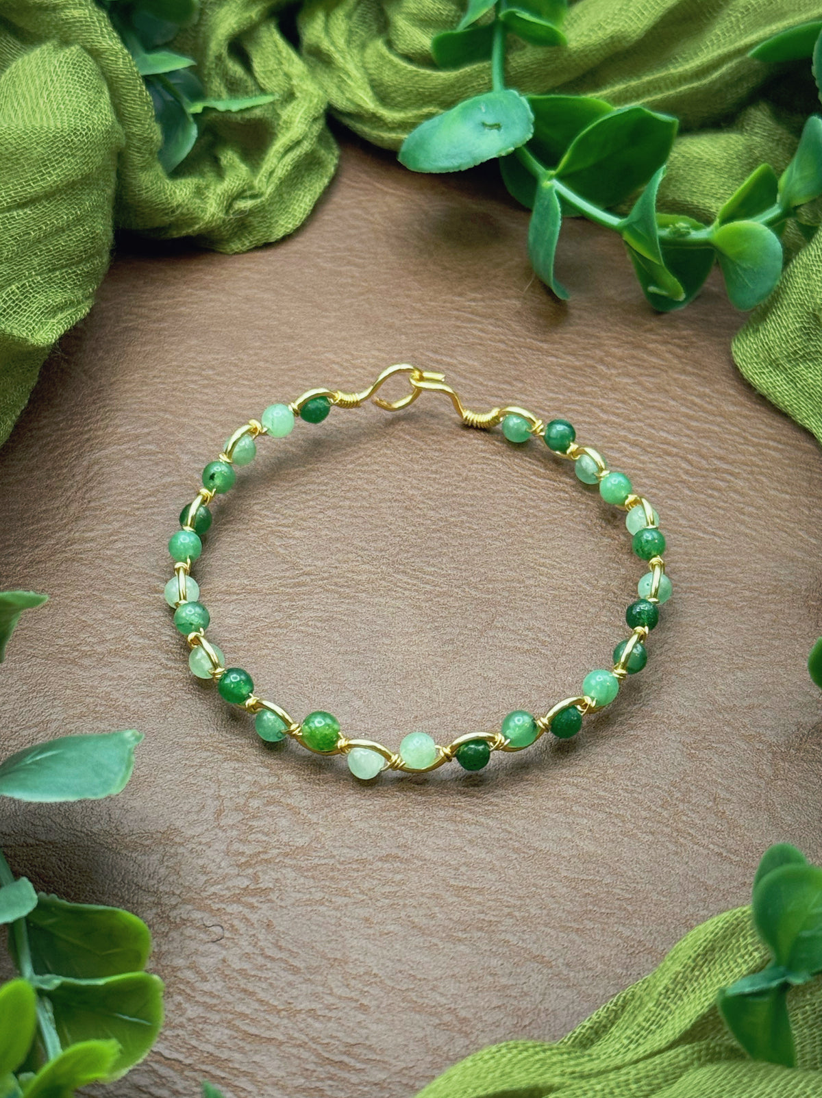 Handmade, wire-wrapped bracelet shaped like a wave, featuring green jade gemstone beads.