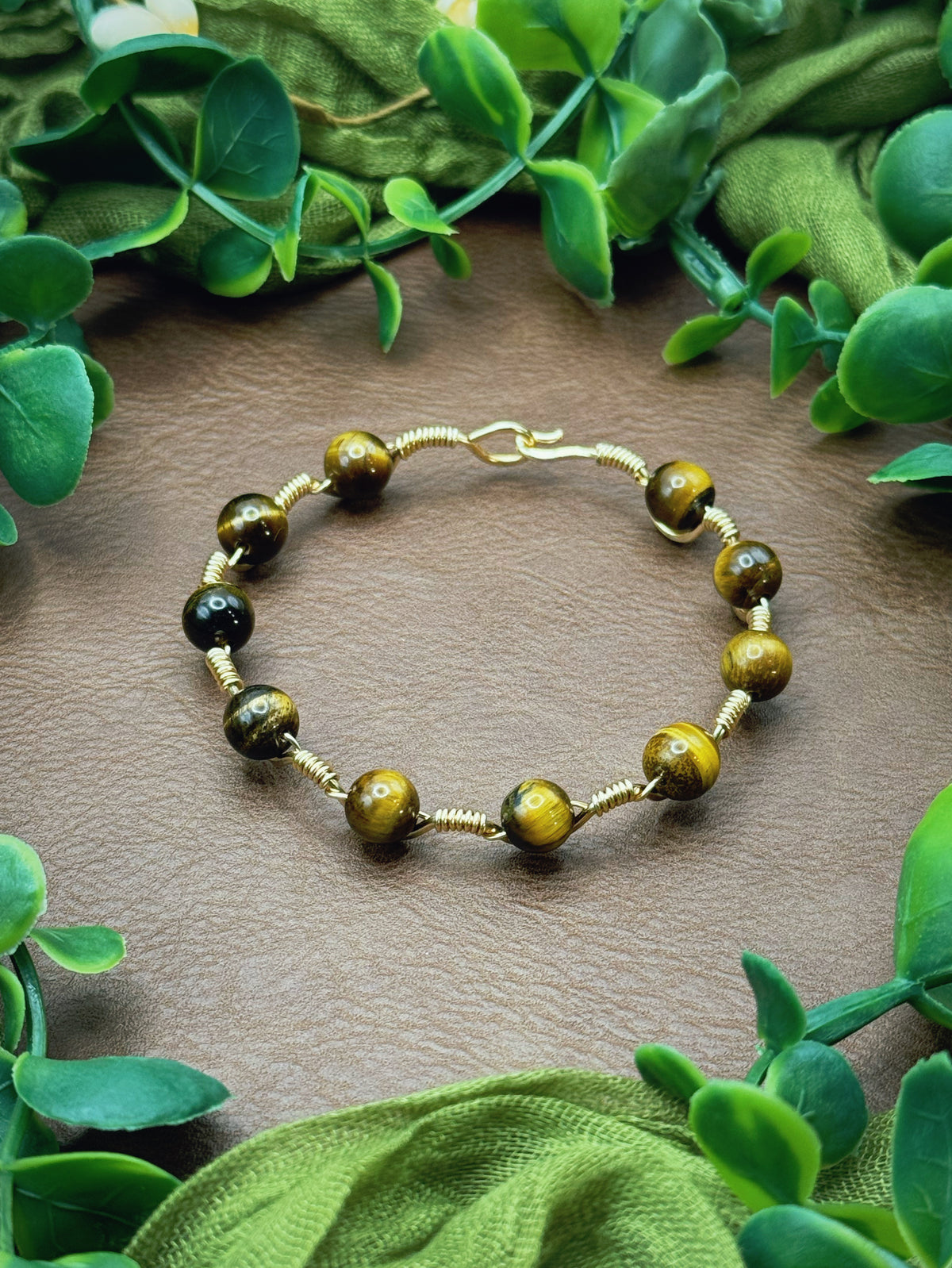 Handmade, wire-wrapped bracelet shaped like a wave, featuring tiger's eye beads.