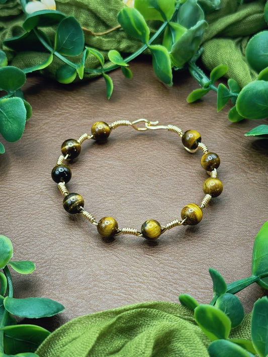 Handmade, wire-wrapped bracelet shaped like a wave, featuring tiger's eye beads.