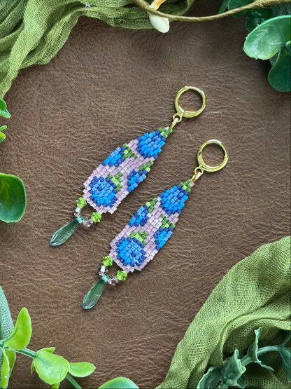 Handmade beaded earrings using 11/0 Miyuki Delica glass seed beads and Czech glass beads on a natural surface with green leaves.