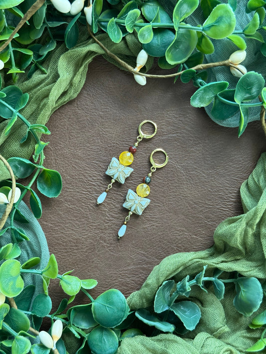 Handmade beaded earrings with gemstone and Czech glass beads on a natural background with green leaves around.
