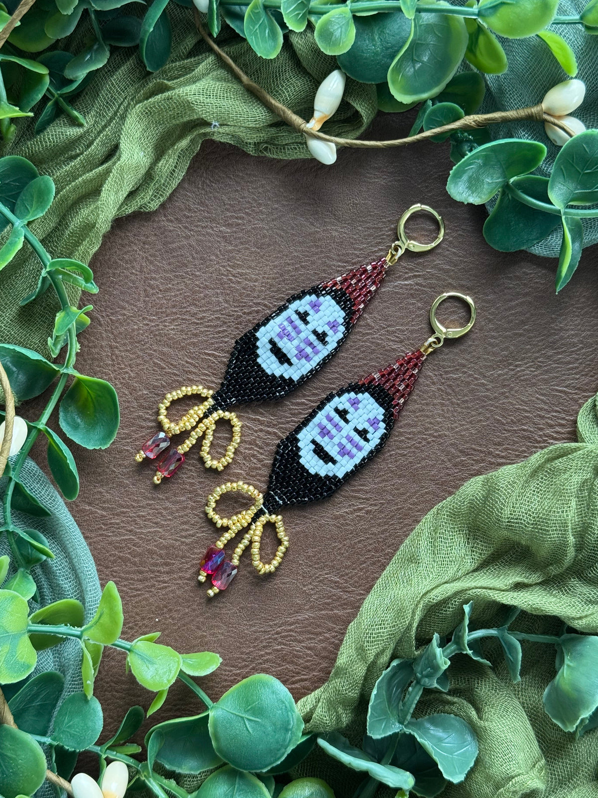 Handmade earrings inspired by Spirited Away, using 11/0 Miyuki Delica glass beads. On a natural background surrounded by green leaves.