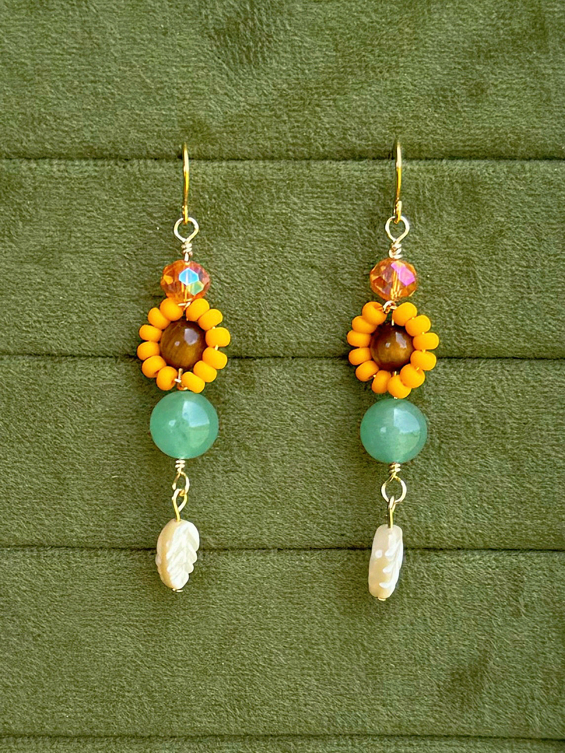 Handmade beaded floral earrings with gemstone and glass beads on an olive green velvet background.