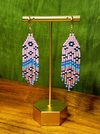 Beaded earrings on a gold stand with a green background.
