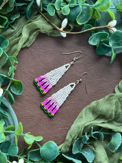 Handmade colorful beaded earrings using 11/0 Miyuki Delica glass seed beads on a natural surface surrounded by greenery.