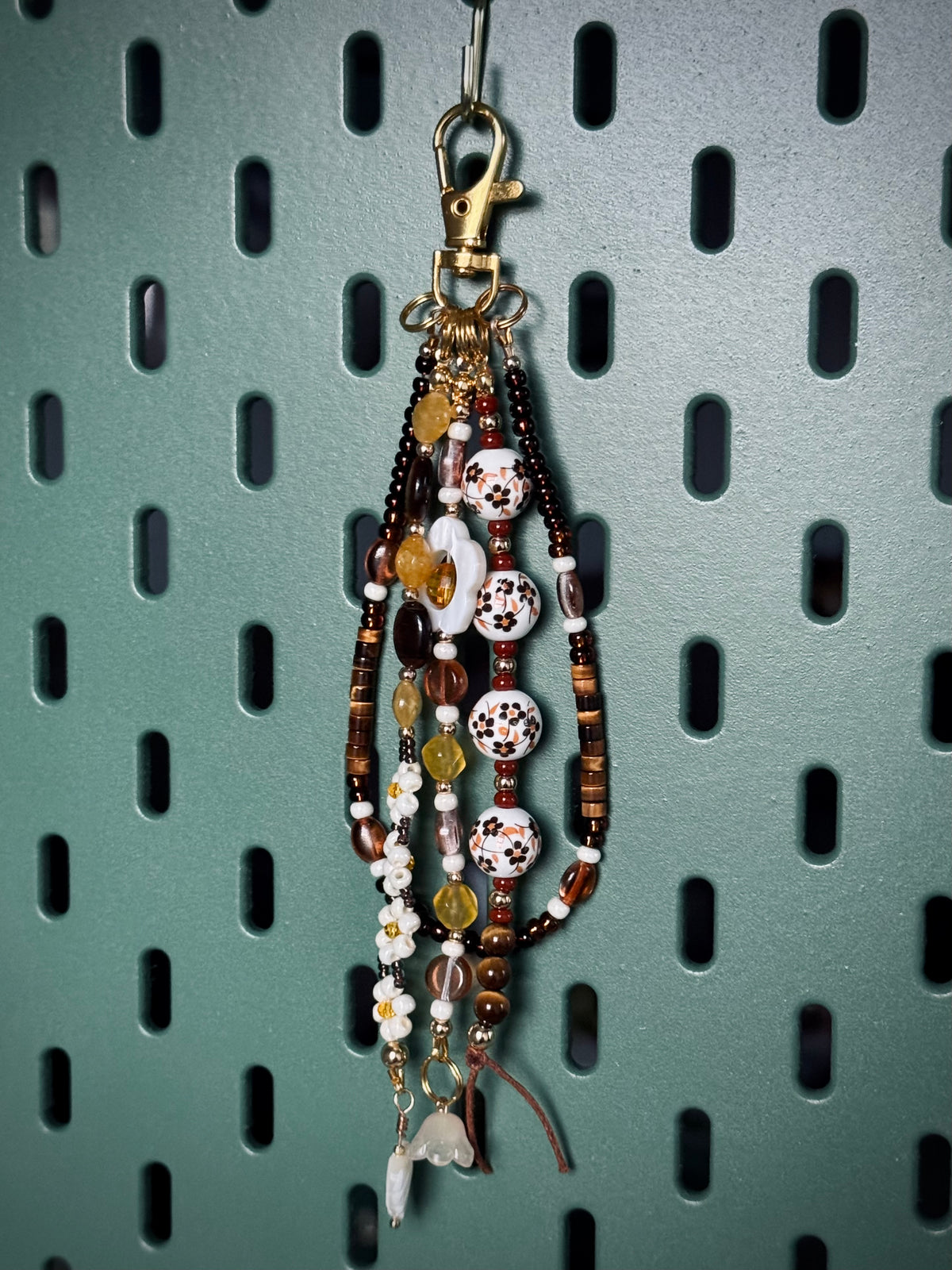 Handmade beaded bag charm keychain with round ceramic beads, white flowers, and tiger's eye beads.
