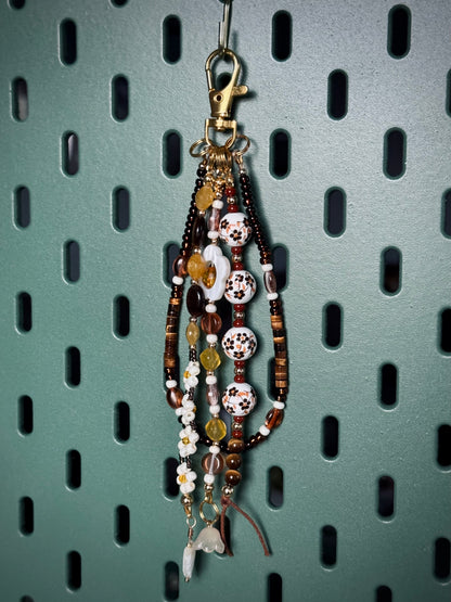 Handmade beaded bag charm keychain with round ceramic beads, white flowers, and tiger's eye beads.
