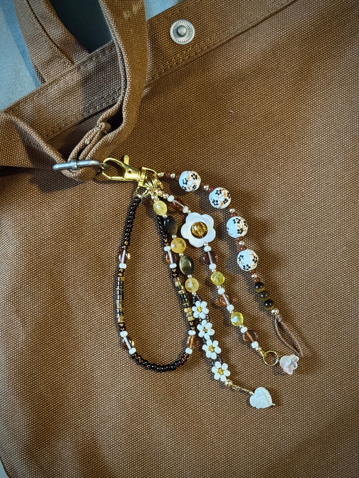 Handmade beaded bag charm keychain with round ceramic beads, white flowers, and tiger's eye beads.