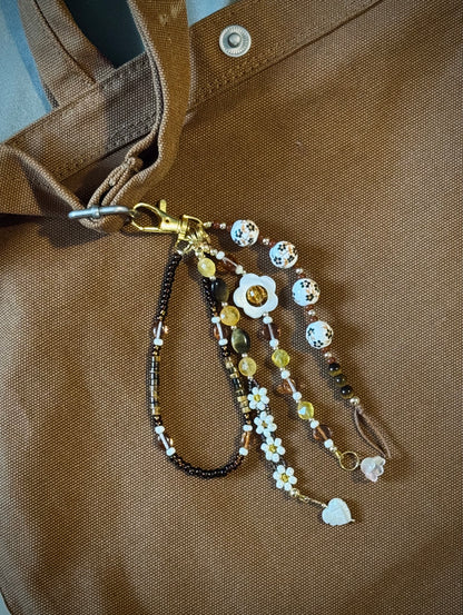 Handmade beaded bag charm keychain with round ceramic beads, white flowers, and tiger's eye beads.