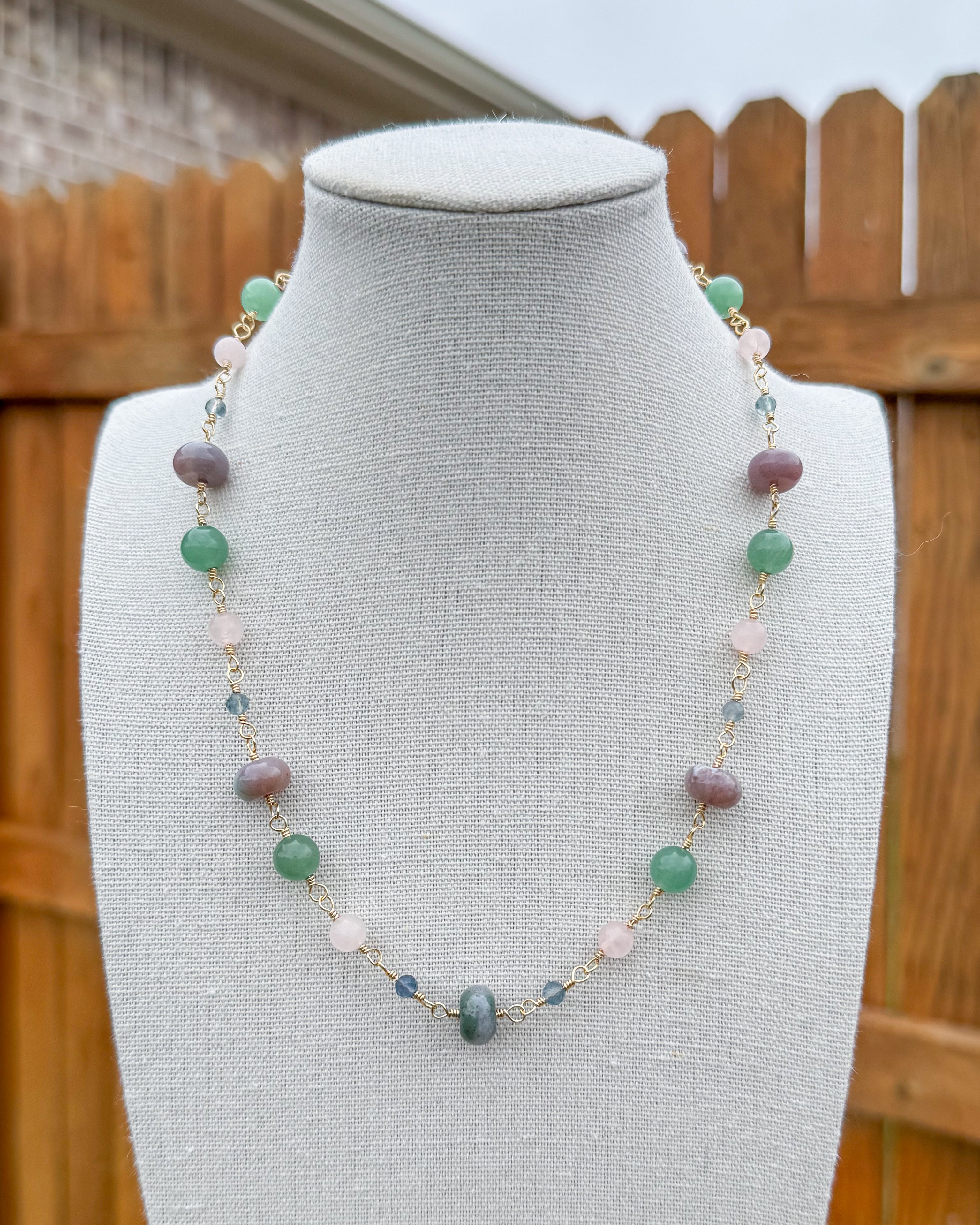 Beaded necklace featuring handmade wire links with blue, green, and pink gemstone beads.