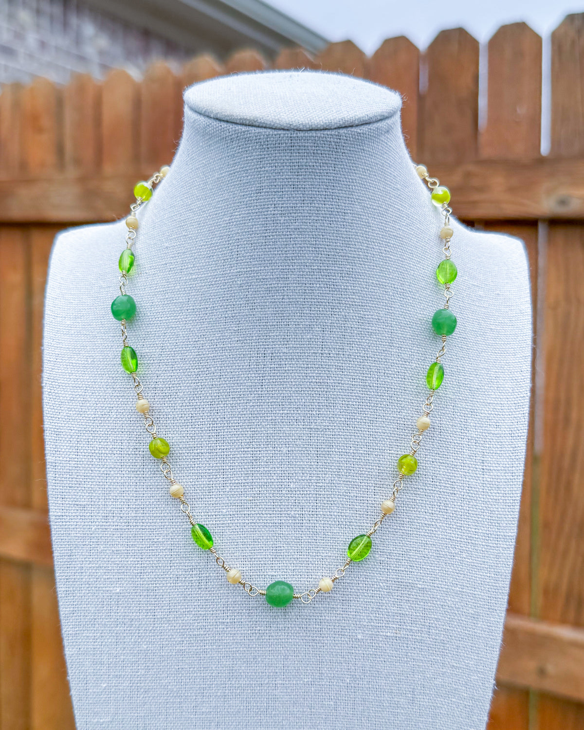 Beaded necklace featuring handmade wire links with green and ivory glass beads.