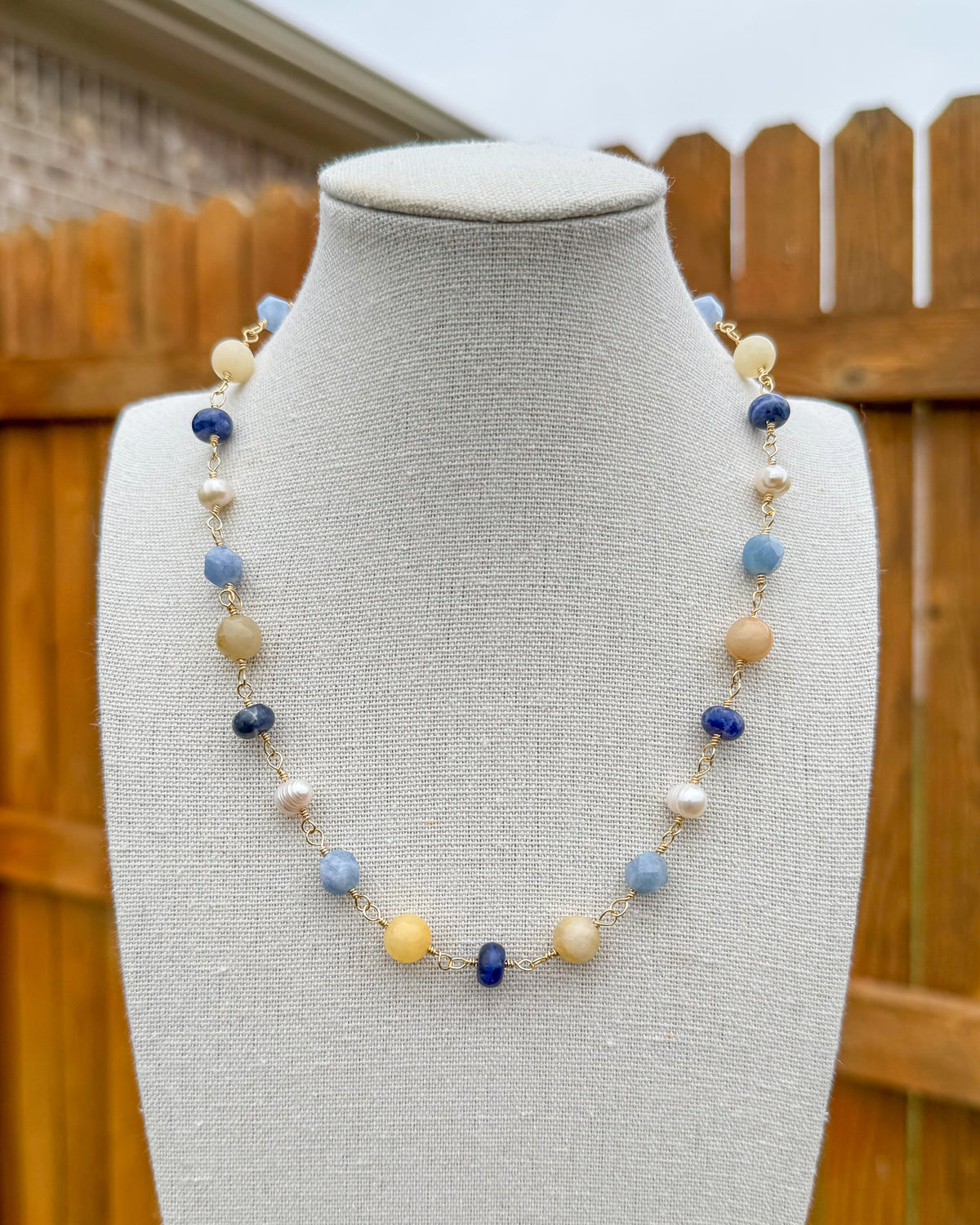 Beaded necklace featuring handmade wire links with blue, yellow, and white gemstone beads and pearls.