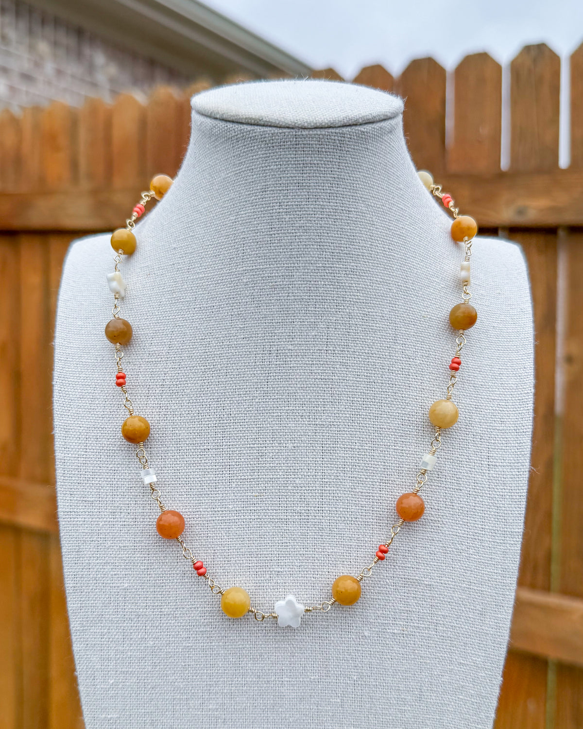 Beaded necklace featuring handmade wire links with yellow, orange, and white gemstone beads and pearls.
